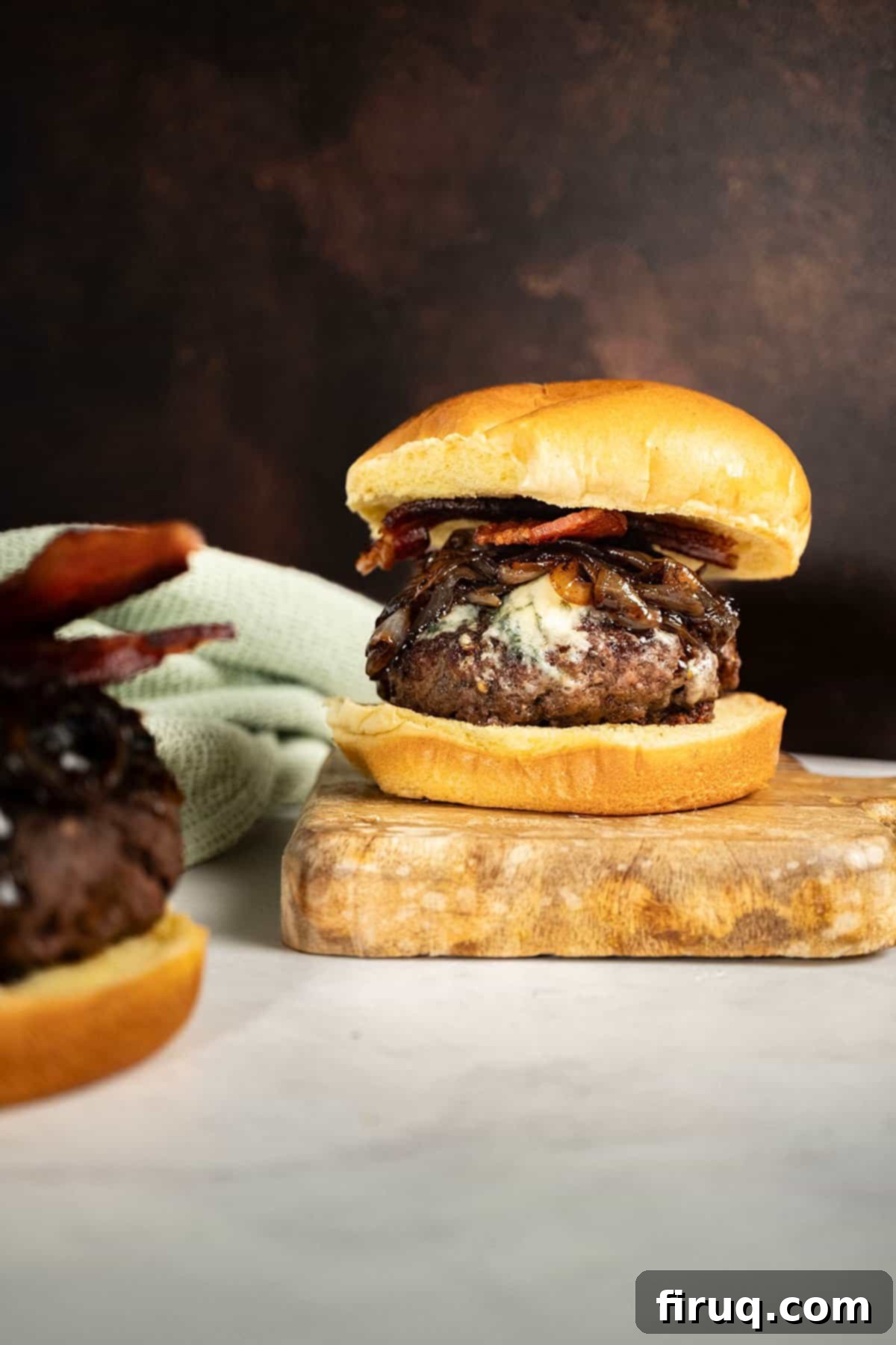 Sizzling Bacon & Bold Blue Cheese Burger 2 Gourmet Bacon Blue Cheese Burger with homemade onion jam on a wooden cutting board, ready to serve.