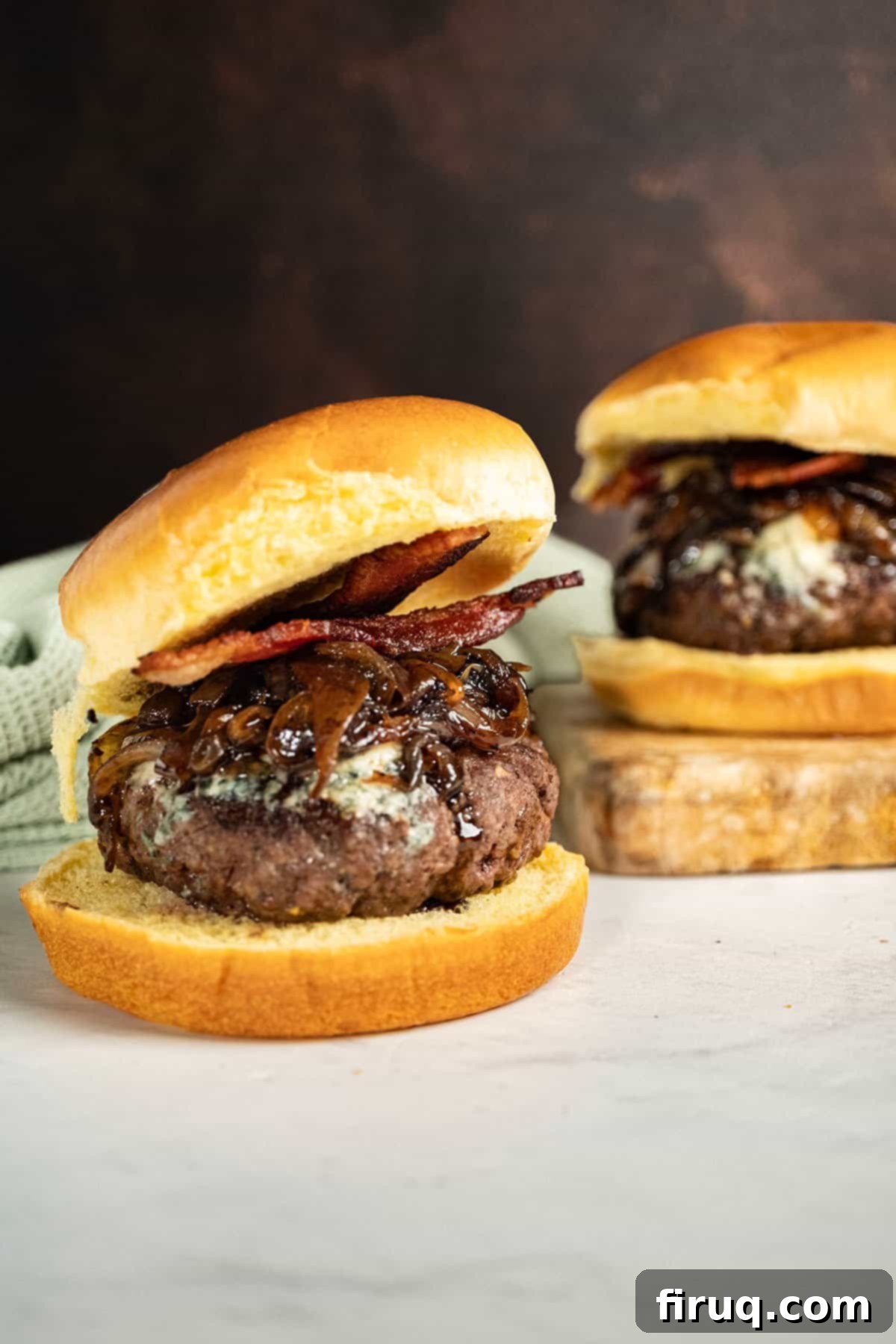 Sizzling Bacon & Bold Blue Cheese Burger 10 Fully assembled Bacon Blue Cheese Burger on a wooden cutting board, garnished and ready to be enjoyed.