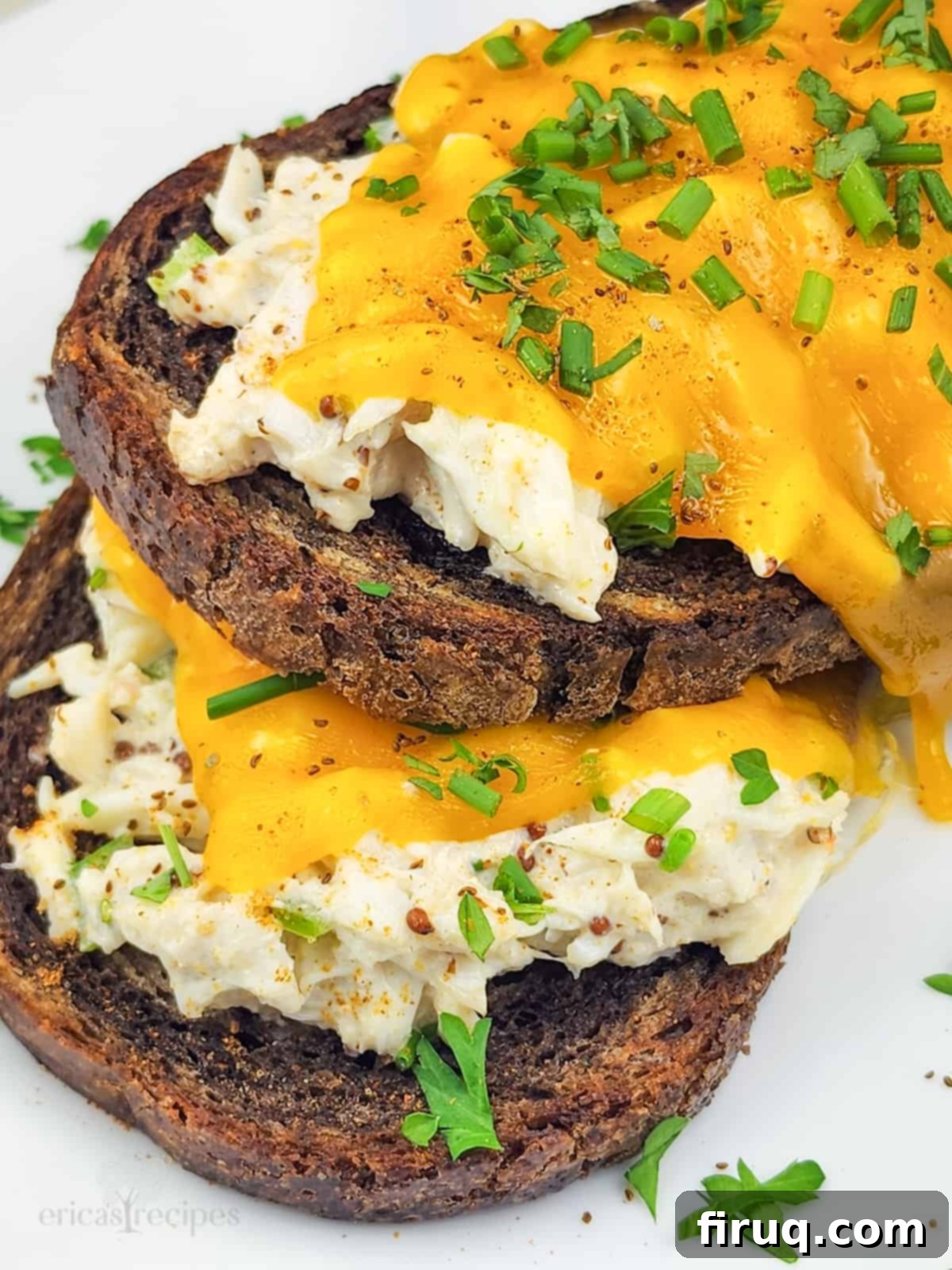 Golden Crab Melt Toast 2 Two open faced crab melt sandwiches on a white plate, garnished with fresh chives, ready to be served.