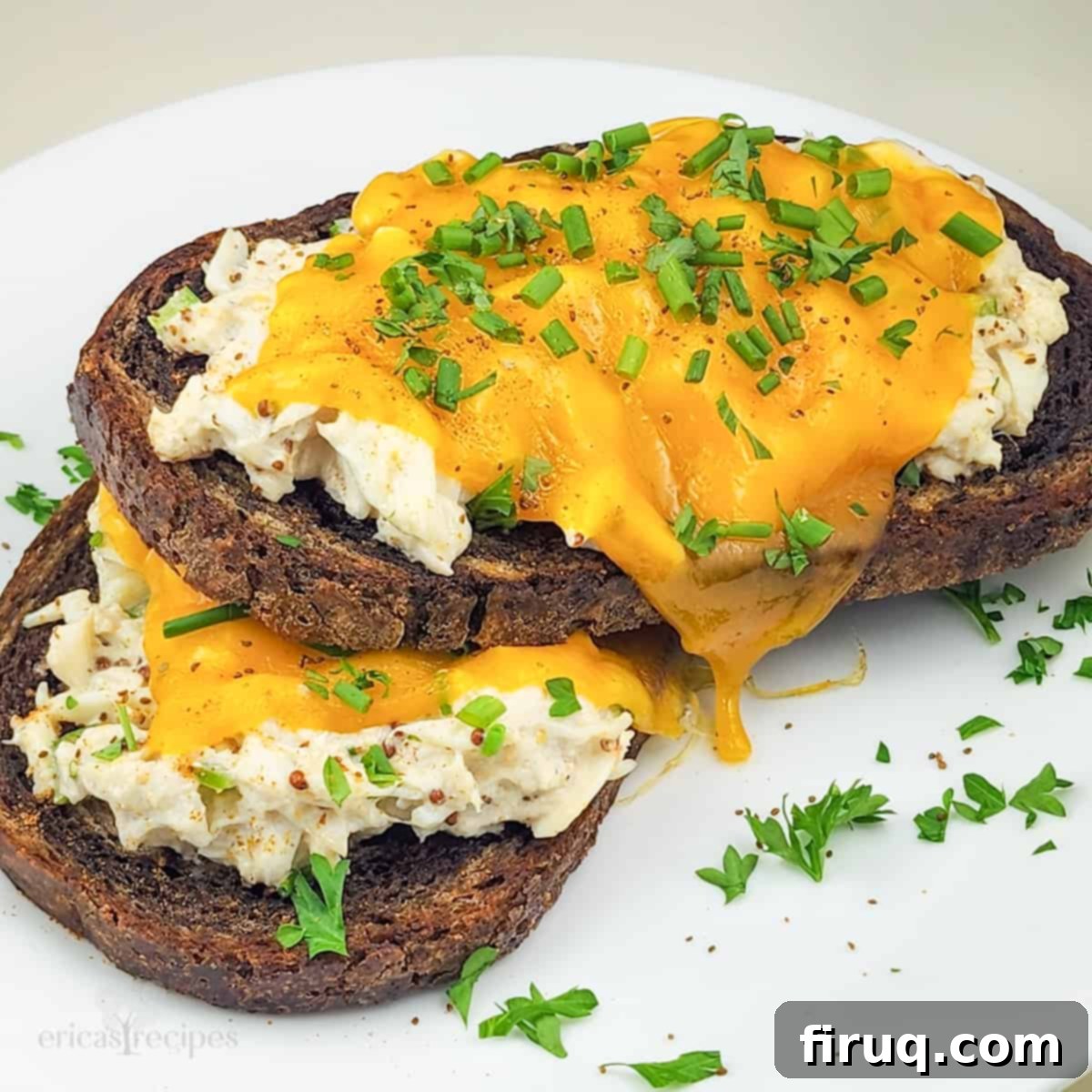 Golden Crab Melt Toast 3 Close-up of two open faced crab melt sandwiches, showcasing the melted smoked cheddar and rich crab salad on marble rye bread.