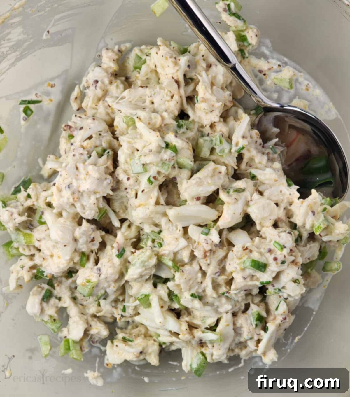 Golden Crab Melt Toast 5 Freshly prepared crab salad in a clear glass bowl with a spoon, showing the lump crabmeat and vibrant seasonings.