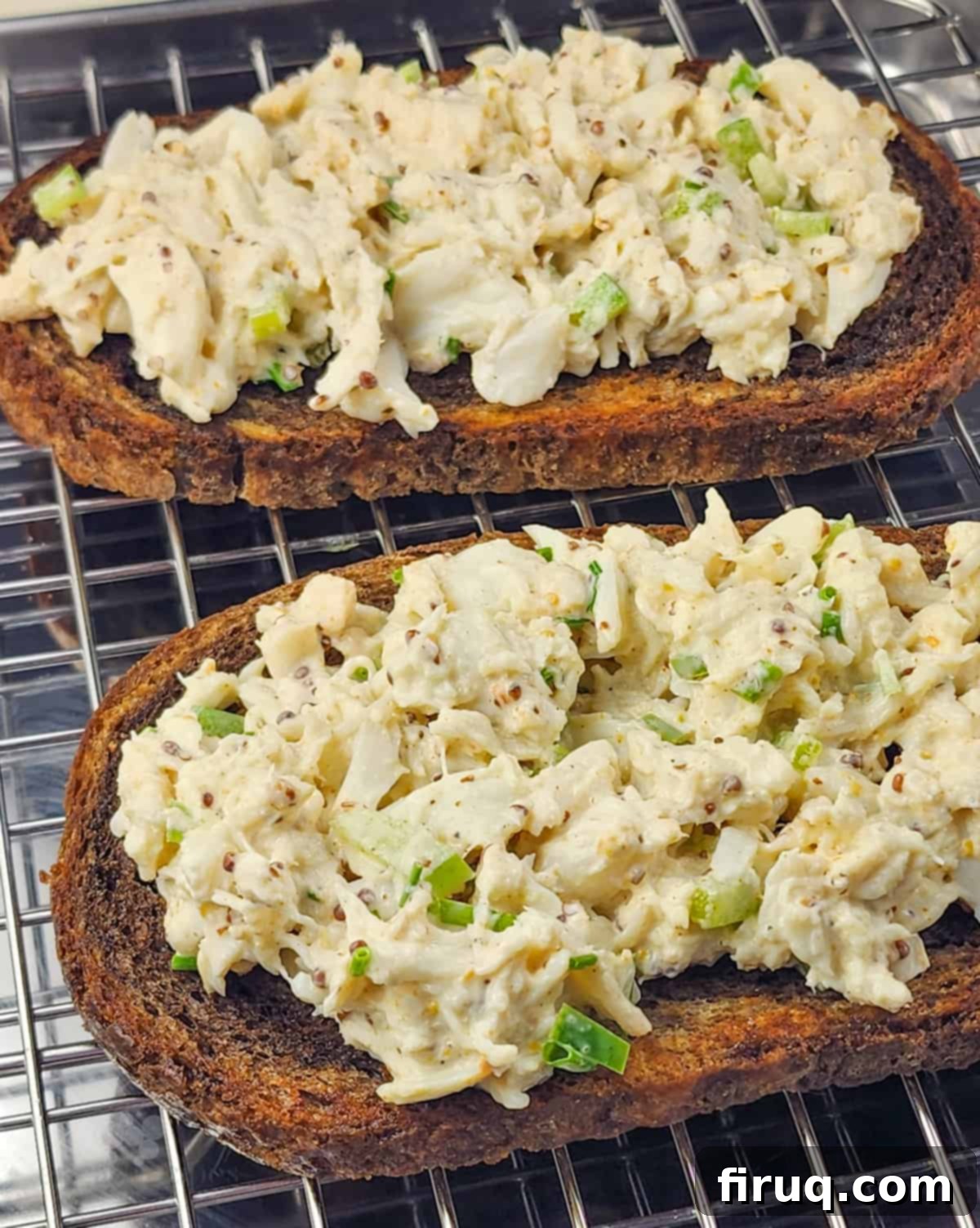 Golden Crab Melt Toast 6 Crab salad generously spread over a slice of toasted bread, topped with a slice of smoked cheddar cheese, ready for broiling.