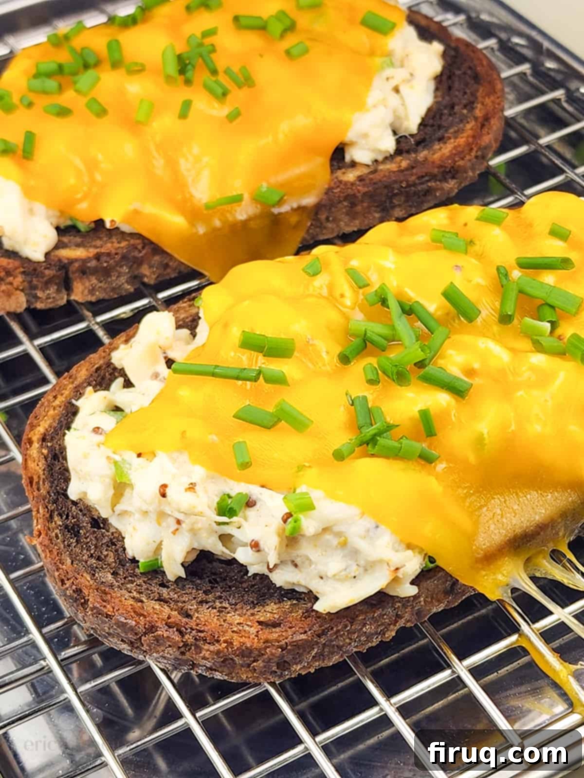 Golden Crab Melt Toast 7 Four open faced crab melt sandwiches placed on a baking rack, with melted cheese and fresh garnishes, ready to be served.