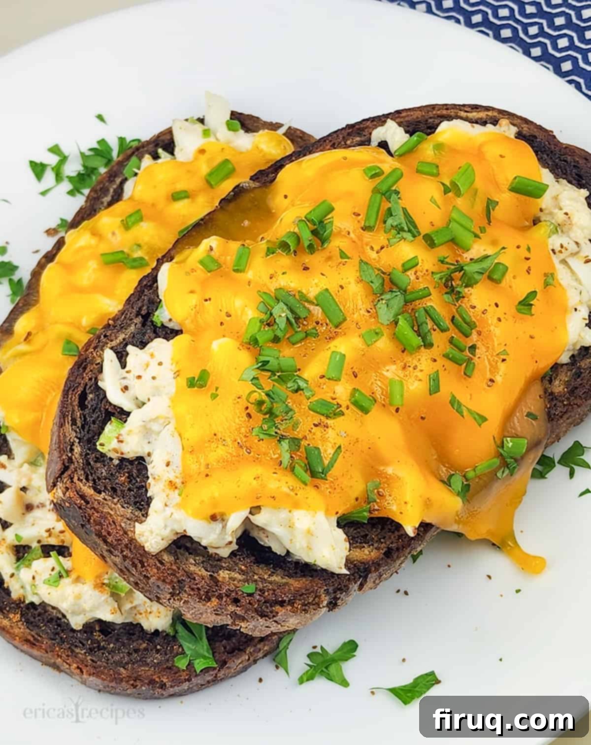 Golden Crab Melt Toast 8 A perfectly cooked open faced crab melt sandwich, golden brown and bubbly, served on a white plate with a sprig of fresh herbs.