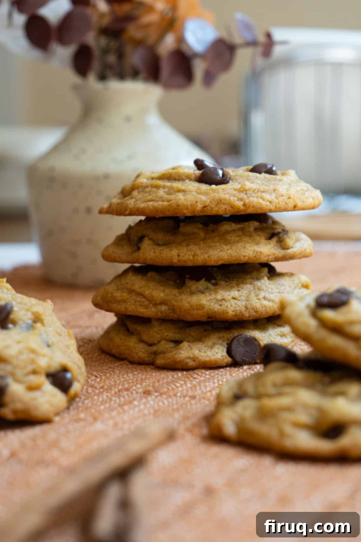 Soft and Chewy Pumpkin Spice Chocolate Chip Cookies 2 Stack of golden-brown chewy pumpkin chocolate chip cookies on a white surface, showcasing their soft texture and chocolate chips.