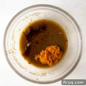 Soft and Chewy Pumpkin Spice Chocolate Chip Cookies 6 Pumpkin puree and vanilla extract being mixed into the creamed butter and sugars, forming a smooth, orange wet ingredient mixture.