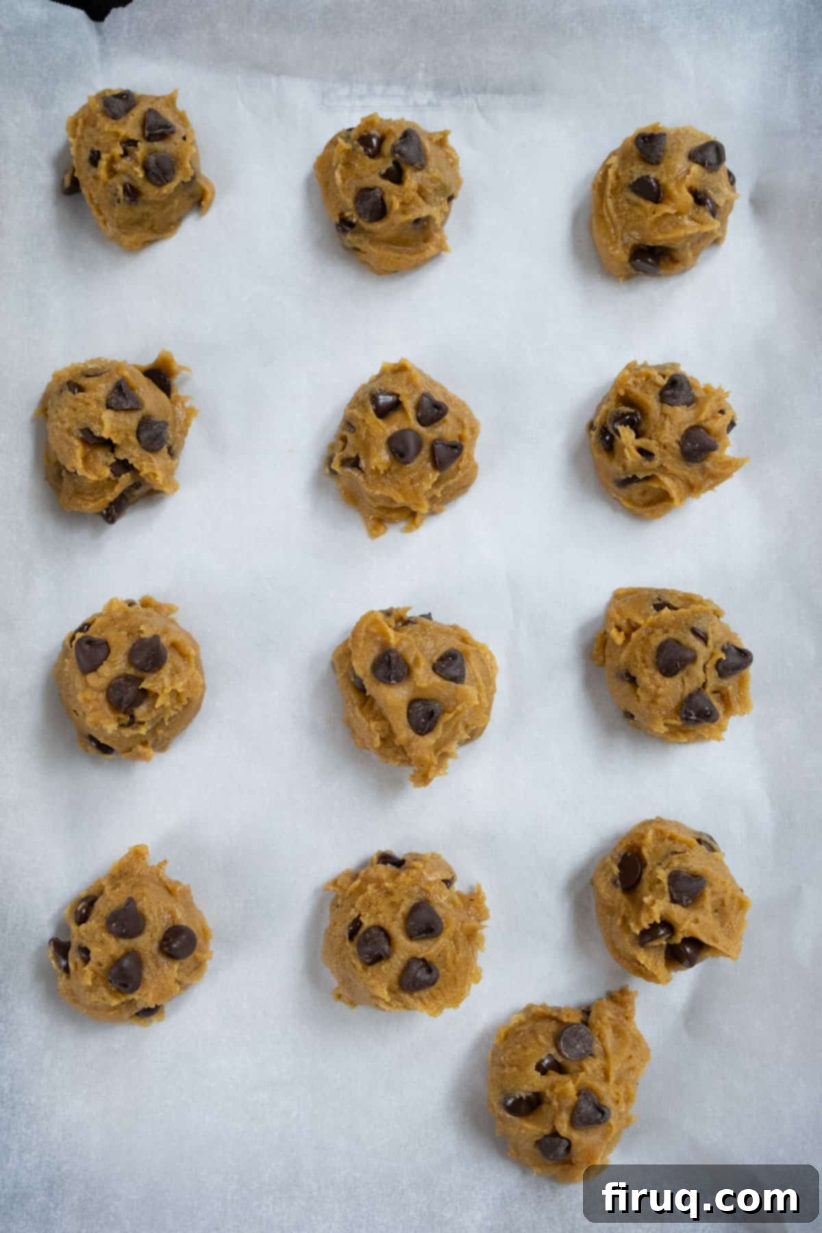 Soft and Chewy Pumpkin Spice Chocolate Chip Cookies 10 Scooped balls of unbaked chewy pumpkin chocolate chip cookie dough arranged on a parchment-lined baking tray, ready for freezing.