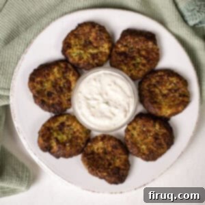 Guilt-Free Air Fryer Zucchini Fritters 12 Golden brown Air fryer zucchini fritters on a plate with a side of creamy aioli dip, garnished with fresh herbs.