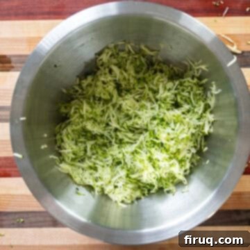 Guilt-Free Air Fryer Zucchini Fritters 5 Grated zucchini in a bowl, ready for moisture removal.