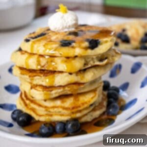 Bright Lemon Ricotta Blueberry Pancakes 12 Lemon ricotta blueberry pancakes covered with syrup with a dollop of ricotta on top.