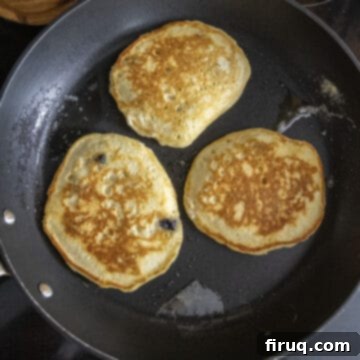 Bright Lemon Ricotta Blueberry Pancakes 10 Pancakes flipped over on the frying pan.