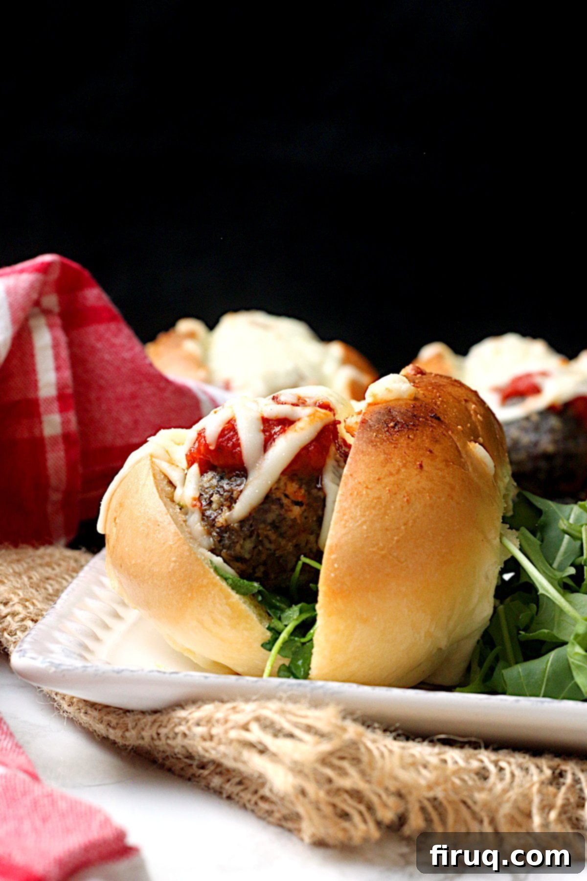 Meatball Sub Ingredients Layered Meatball sub on a square white plate.