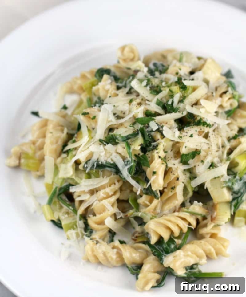 Gluten-Free Velvet Spinach & Leek Rotini 3 rotini pasta with leeks and spinach on a white plate, topped with cheese