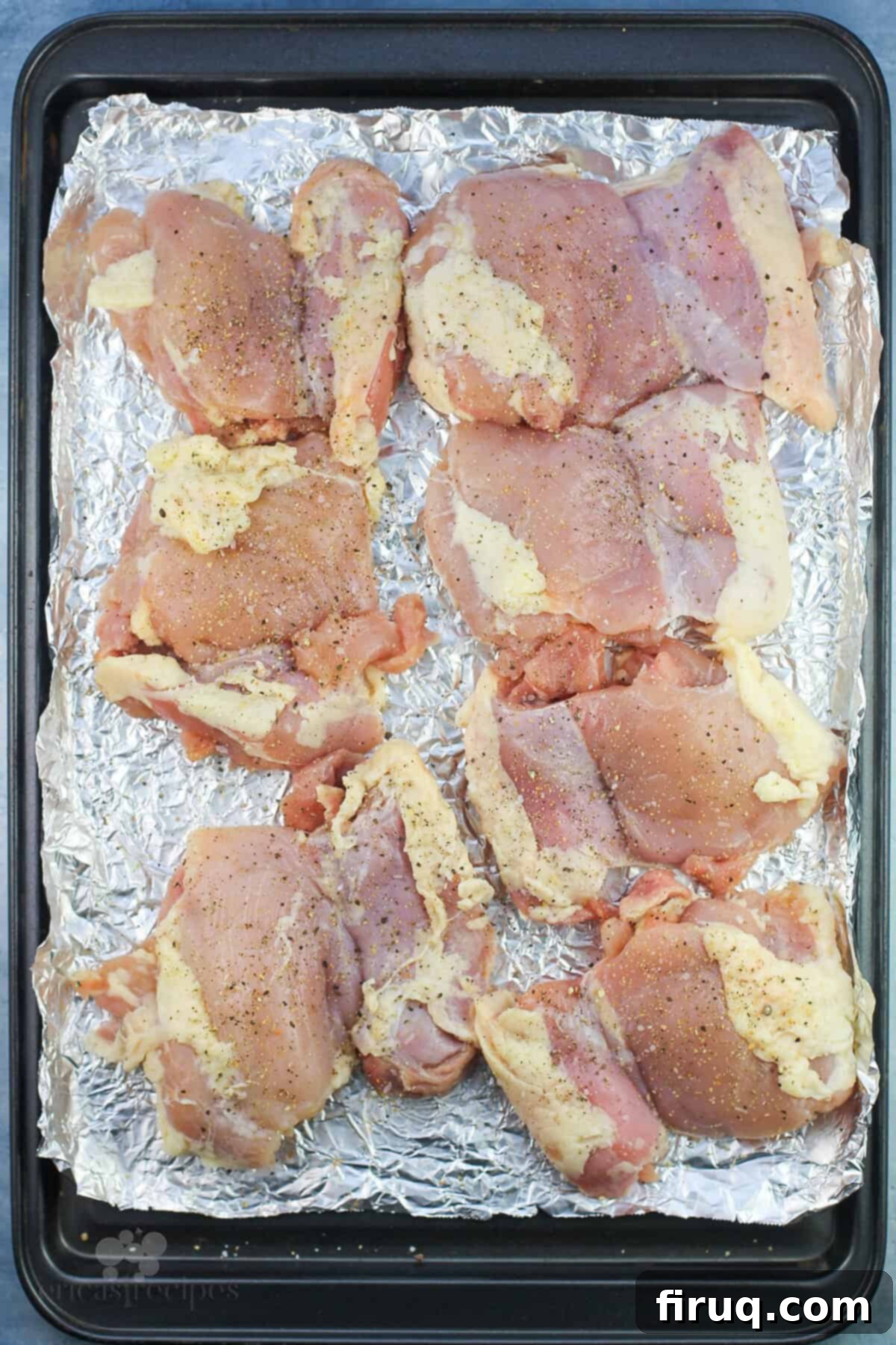 Comforting Chicken Zucchini Bake 4 Uncooked boneless, skinless chicken thighs laid out on a baking sheet, ready for preparation.