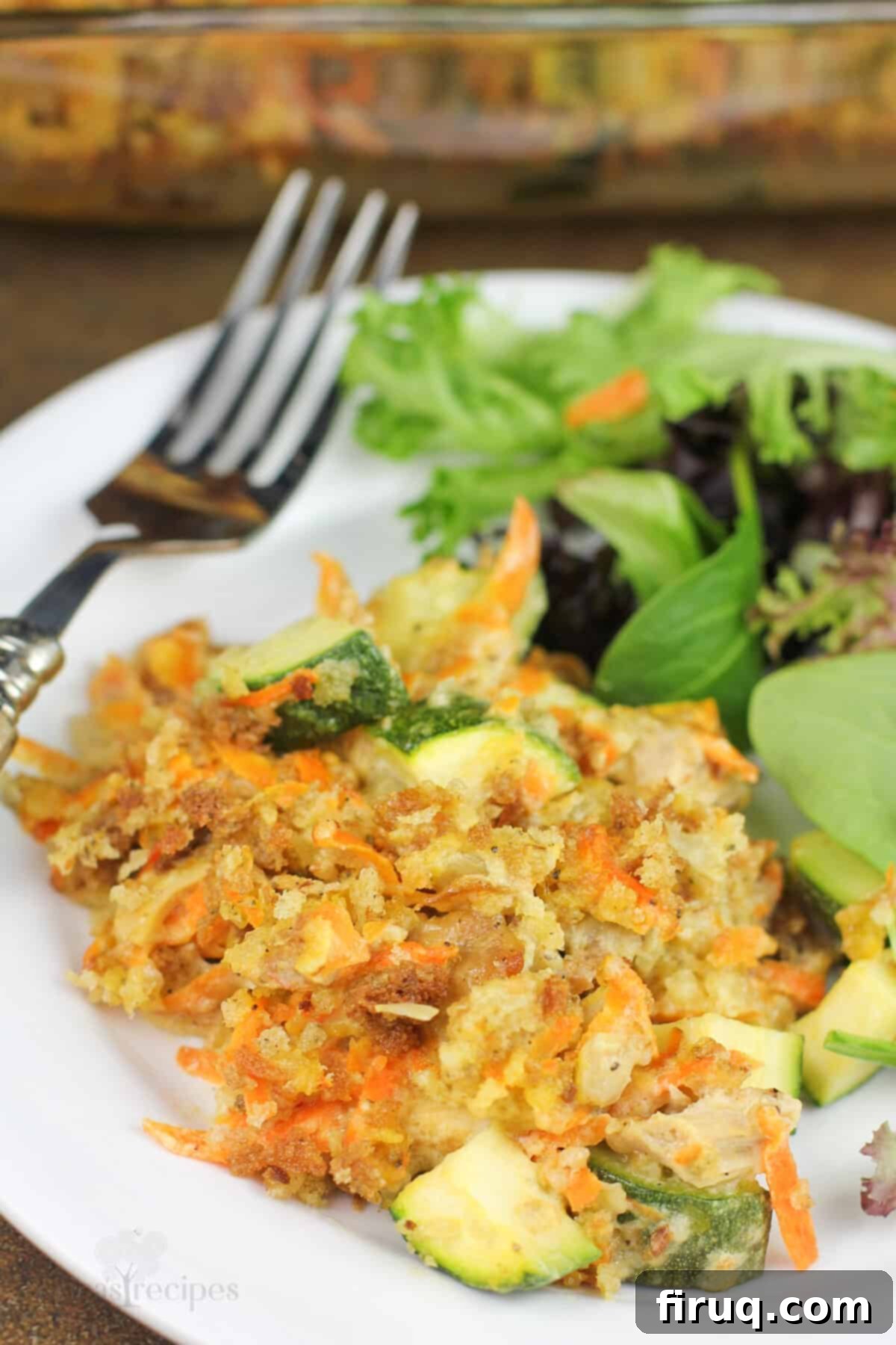Comforting Chicken Zucchini Bake 10 A plated portion of chicken zucchini casserole served with a fresh green salad on a white plate, emphasizing a complete meal.