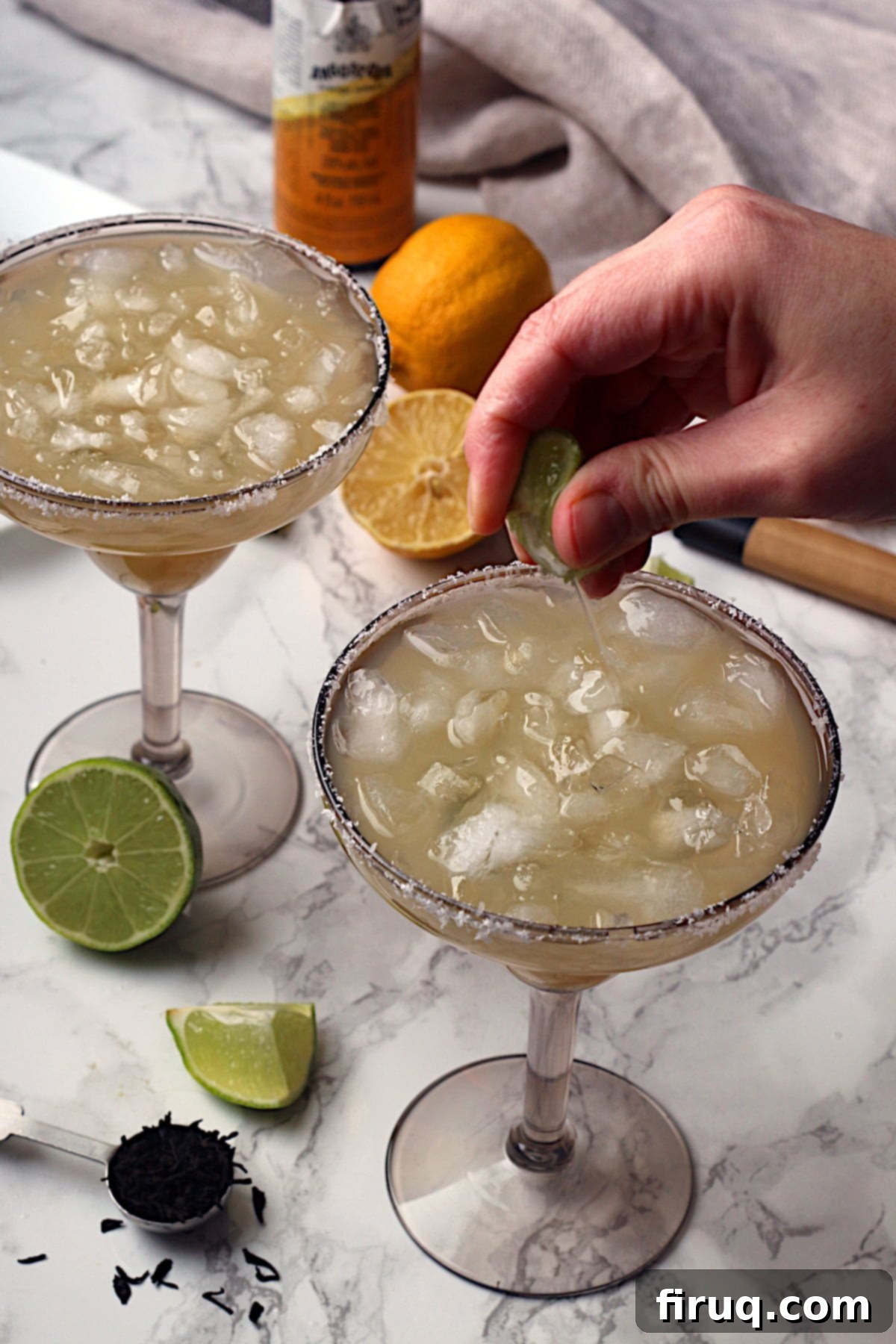 Fresh Lime Juice for Margarita A hand squeezing lime juice into a non-alcoholic lime margarita.