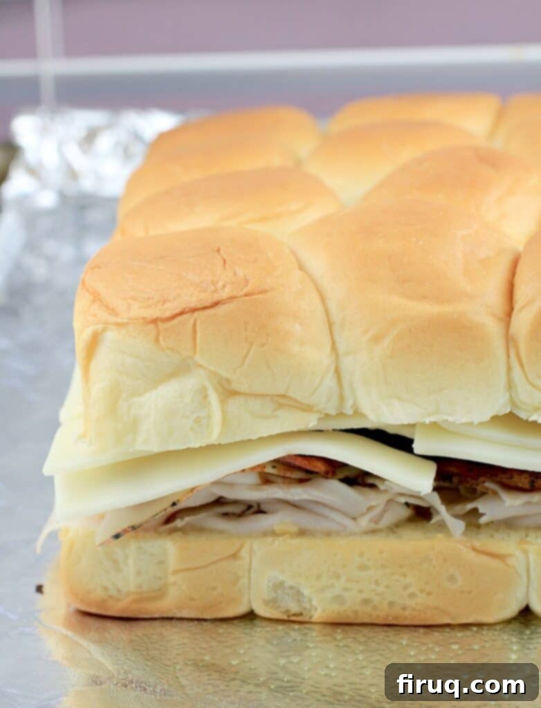 Aloha Maple Bacon Turkey Sliders 8 Side view of fully assembled turkey sliders on Hawaiian rolls, with all layers in place, ready for the final butter brush and baking.