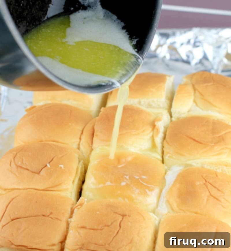 Aloha Maple Bacon Turkey Sliders 9 Melted butter being generously poured over the top of the assembled Hawaiian roll turkey sliders, ensuring a rich, golden crust during baking.