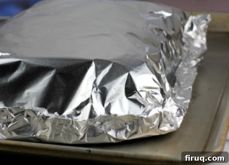 Aloha Maple Bacon Turkey Sliders 10 A baking sheet with the prepared Hawaiian roll turkey sliders, encased in aluminum foil and ready for the oven, ensuring even cooking and moisture retention.
