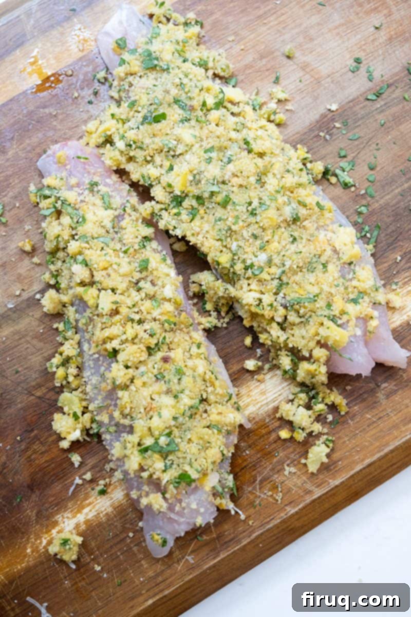 Emerald Zest Snapper 4 Lemon pistachio crusted fish fillets on a baking sheet before cooking.