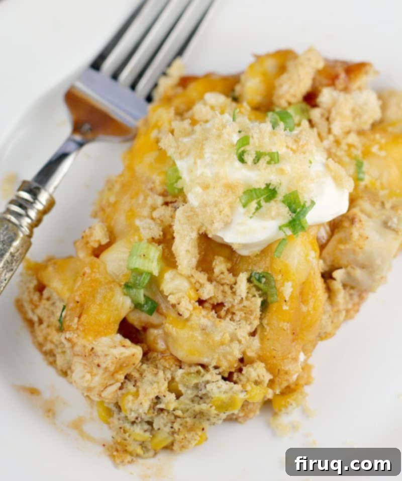 Unwrapped Keto Chicken Tamale Casserole 9 Top down view of finished casserole plated on a white plate, topped with sour cream and pork rind crumbs