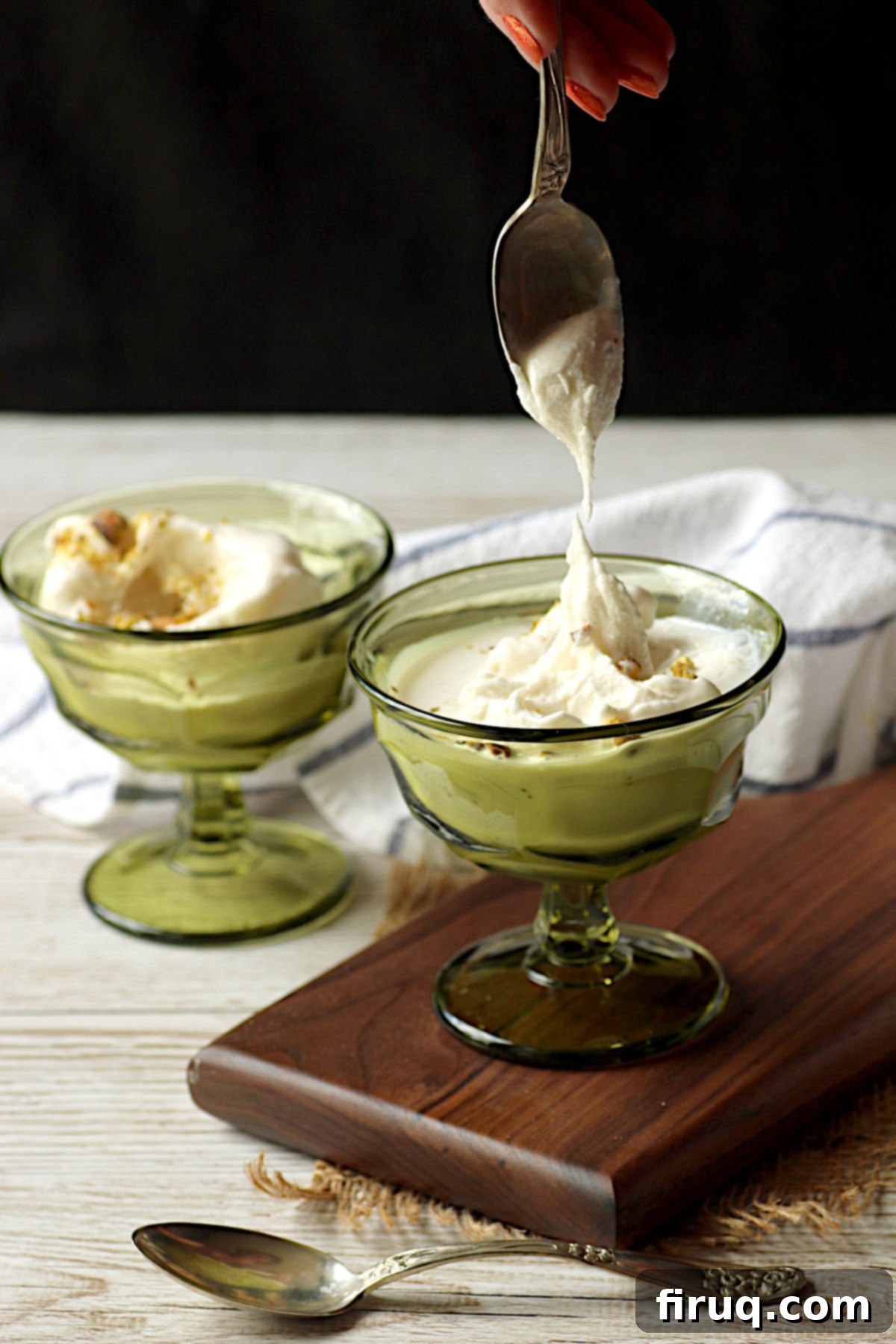 Scooping Booza-Inspired Ice Cream A hand scooping a spoonful of creamy, stretchy Booza-Inspired Ice Cream from a small green dish.