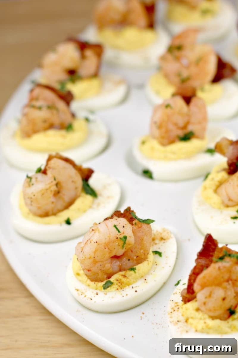 Zesty Creole Shrimp Deviled Eggs with Crispy Bacon 6 creole shrimp recipe on deviled eggs with bacon on a white platter; parsley sprinkled overtop, close-up shot of the finished appetizer