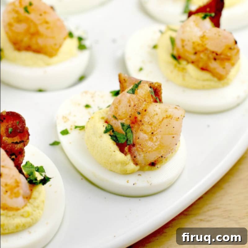 Zesty Creole Shrimp Deviled Eggs with Crispy Bacon 9 close view of a finished deviled egg, garnished with shrimp, bacon, and parsley