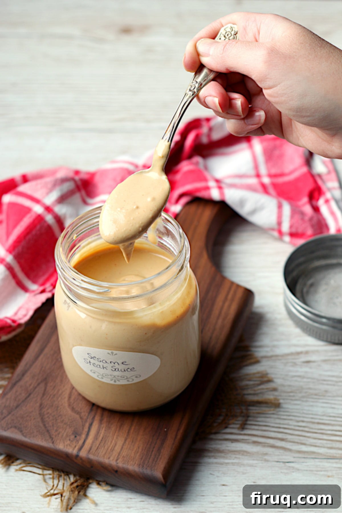 Sawmill Sesame Steak Sauce 3 A spoon scooping a spooful of sesame steak sauce from a jar.
