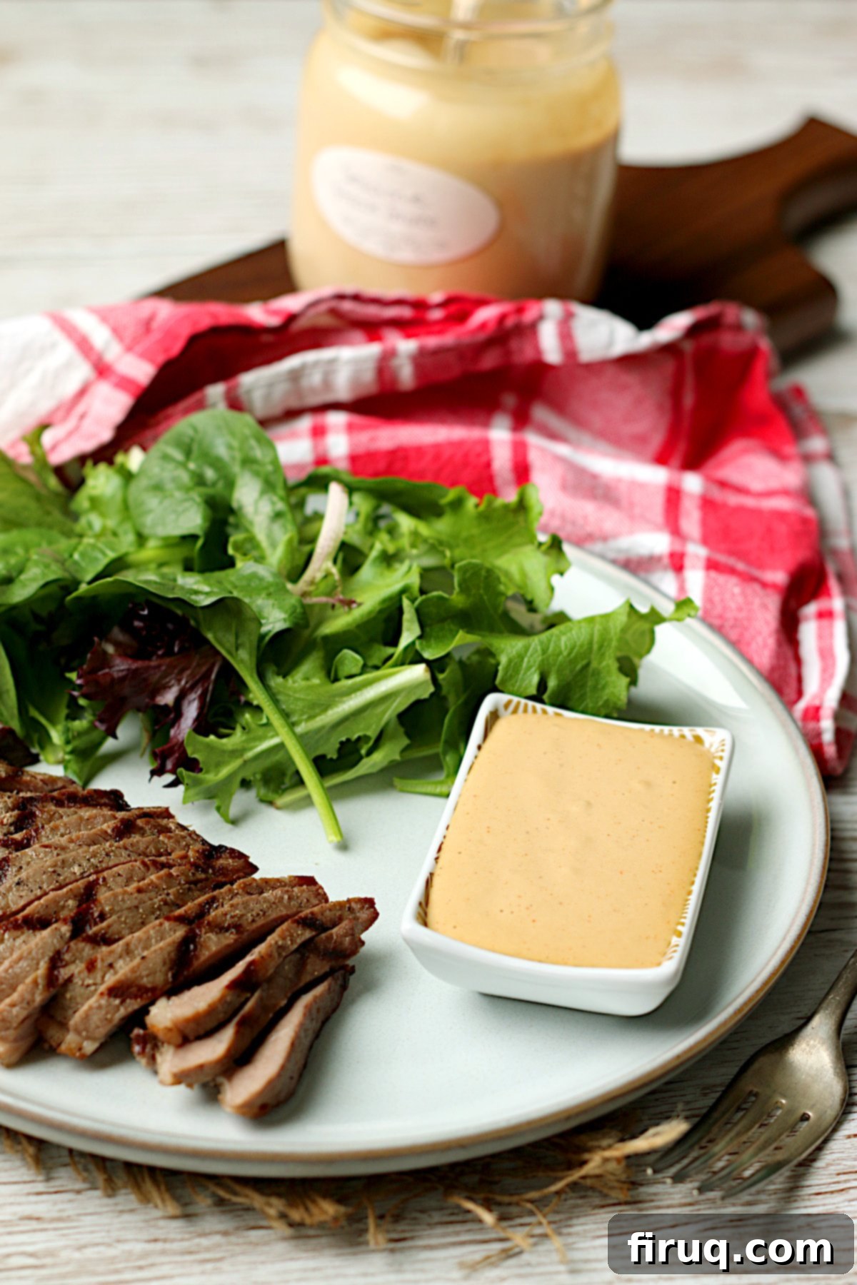 Sawmill Sesame Steak Sauce 4 Sliced grilled steak with salad and a small dish of Sesame Steak Sauce on a white plate.