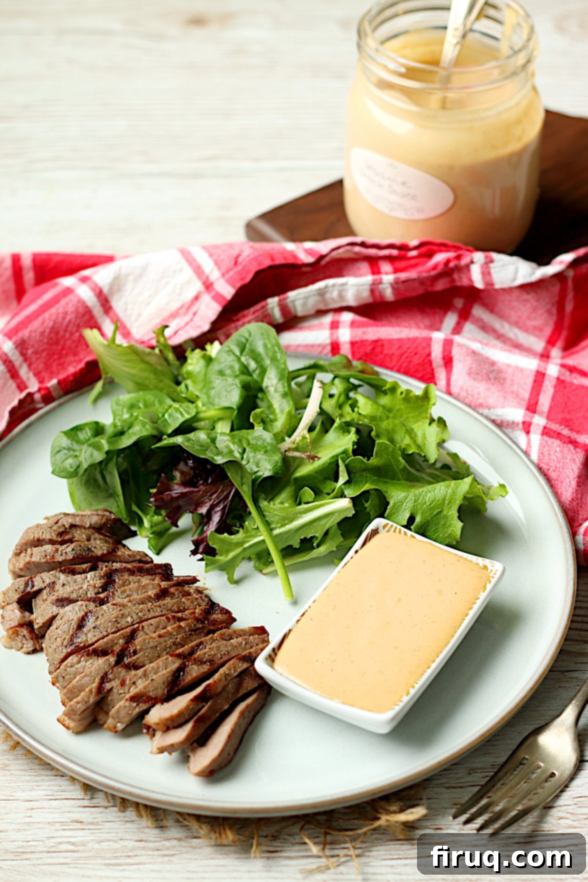 Sawmill Sesame Steak Sauce 5 Sliced grilled steak with salad and a small dish of Sesame Steak Sauce on a white plate.