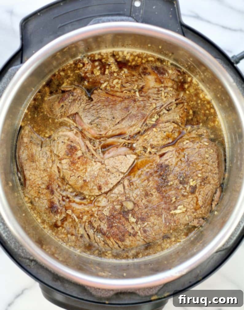 Zesty Cajun Instant Pot Pot Roast 7 top down view of the instant pot pot roast seared, in the bear-garlic mixture, before adding the remaining ingredients