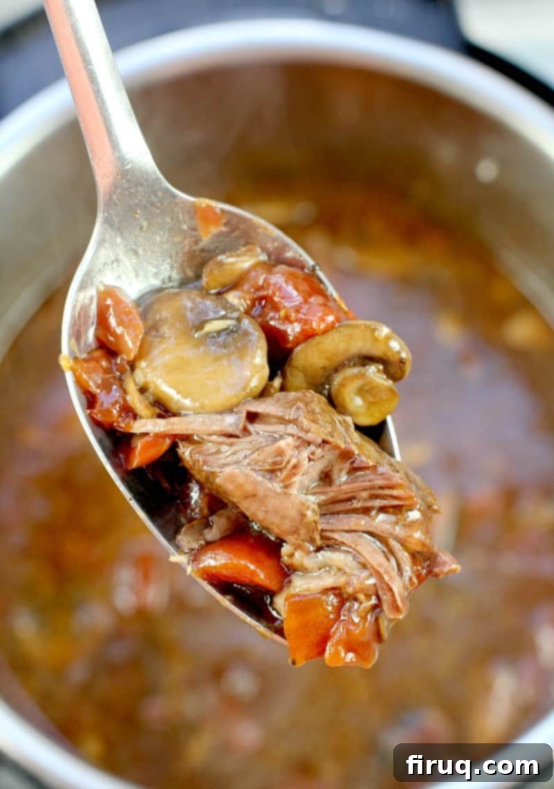 Zesty Cajun Instant Pot Pot Roast 9 a large serving spoon scooping up cooked pot roast with beer, rest of the pot and recipe are in the background