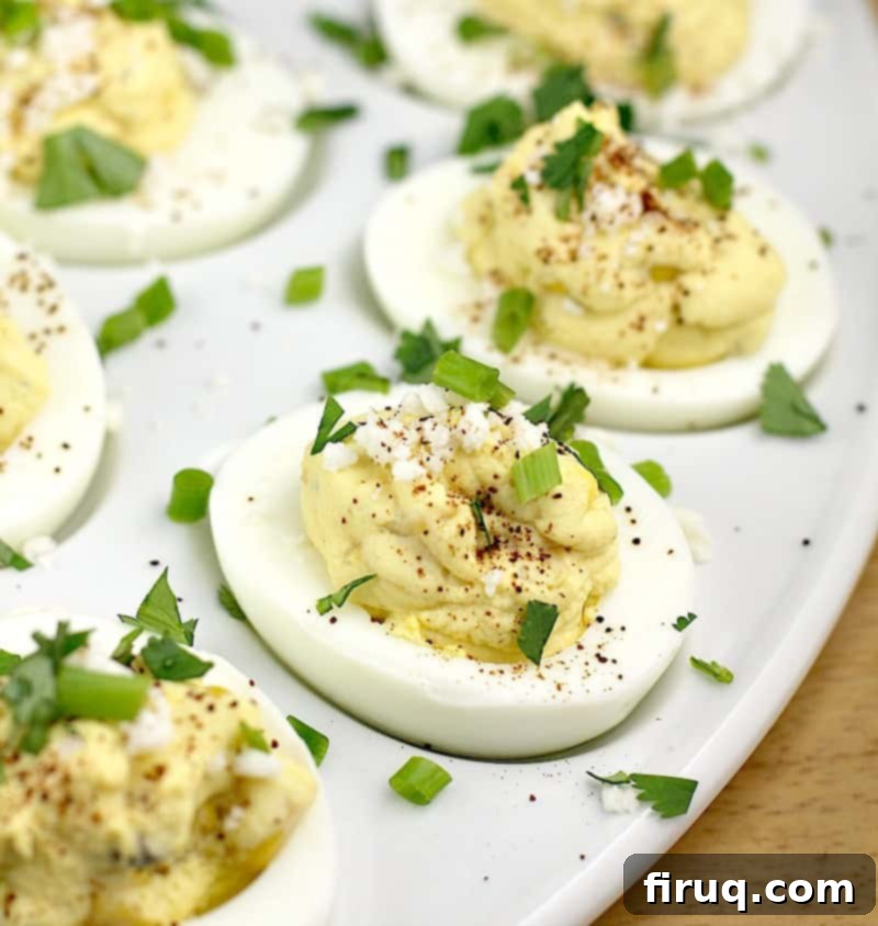 Elote Deviled Eggs 12 Mexican street corn deviled eggs on a white plate, resting on a wooden cutting board