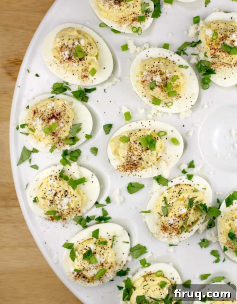 Elote Deviled Eggs 10 A top-down view of multiple Mexican-style deviled eggs, showcasing their vibrant colors and garnishes on a white platter