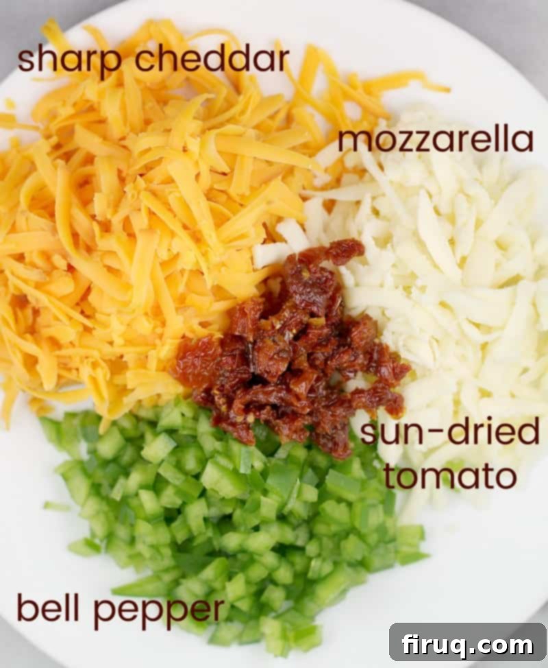 Bayou Mac and Cheese 6 view of the ingredients in a bowl: cheddar, mozzarella, sun-dried tomato, and green bell pepper