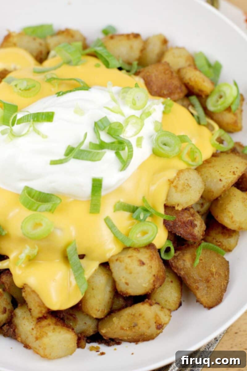 Zesty Cheesy Potato Bites 2 prepared potatoes in a white bowl topped with nacho sauce, sour cream, and green onion