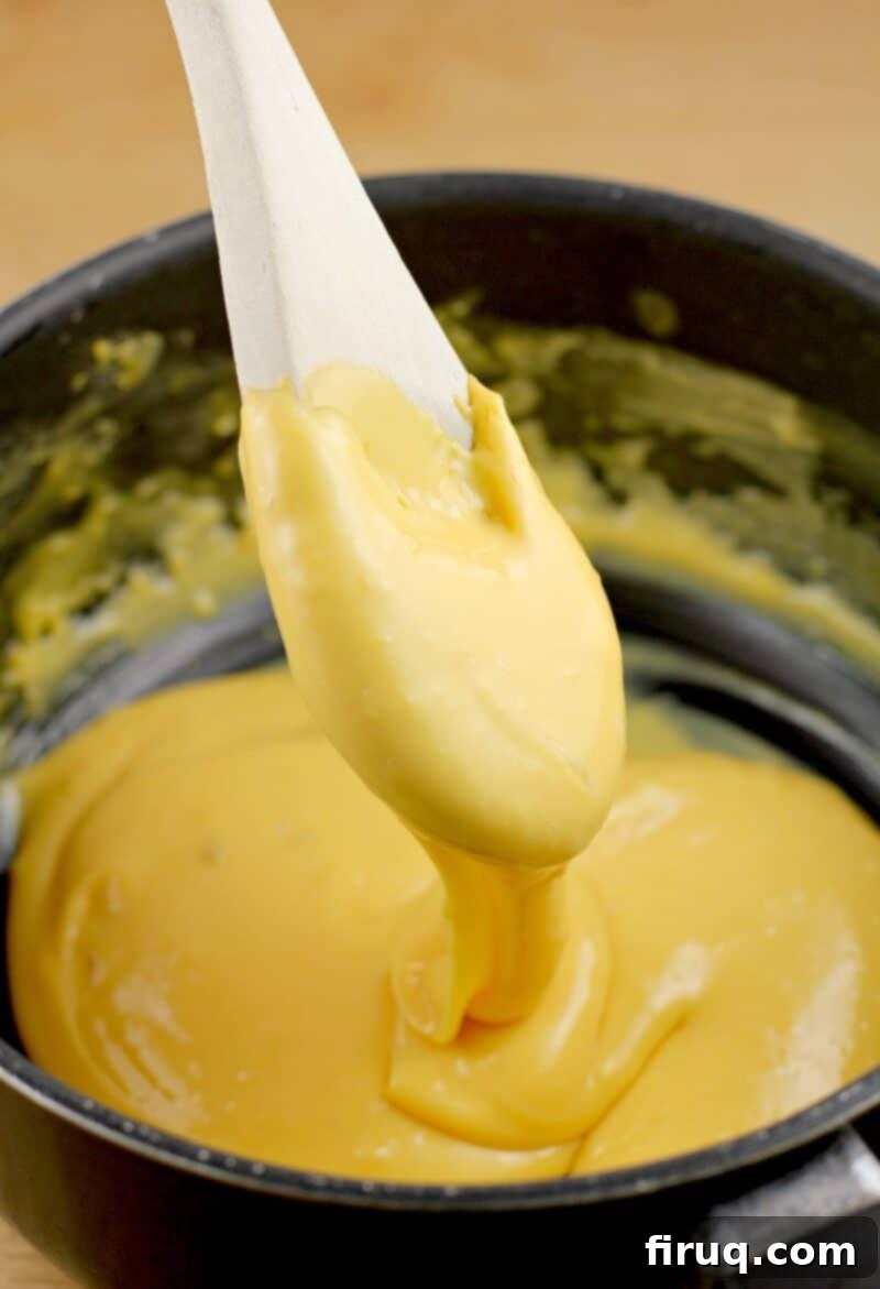 Zesty Cheesy Potato Bites 7 spoon holding nacho sauce dripping in a pan