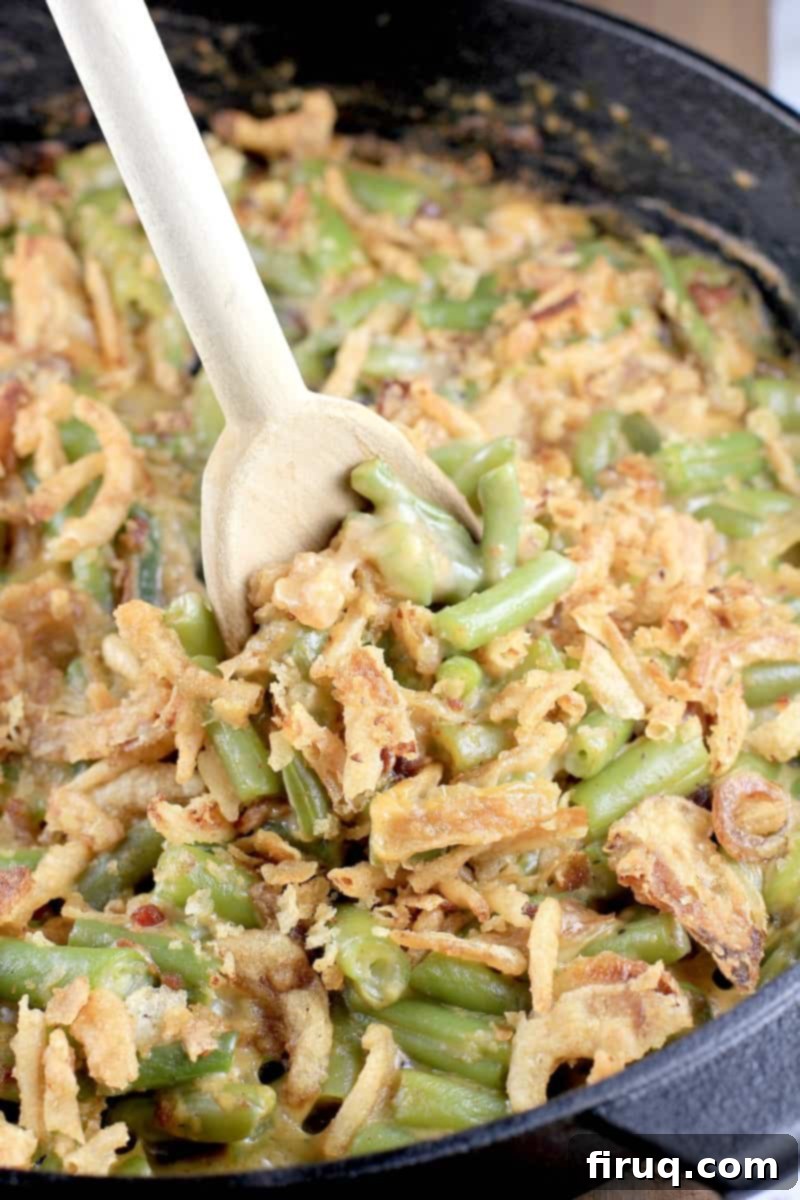 Grilled Green Bean Casserole with Crispy Bacon 11 A wooden spoon lifting a serving of smoky grilled green bean casserole with crispy fried onions on top.