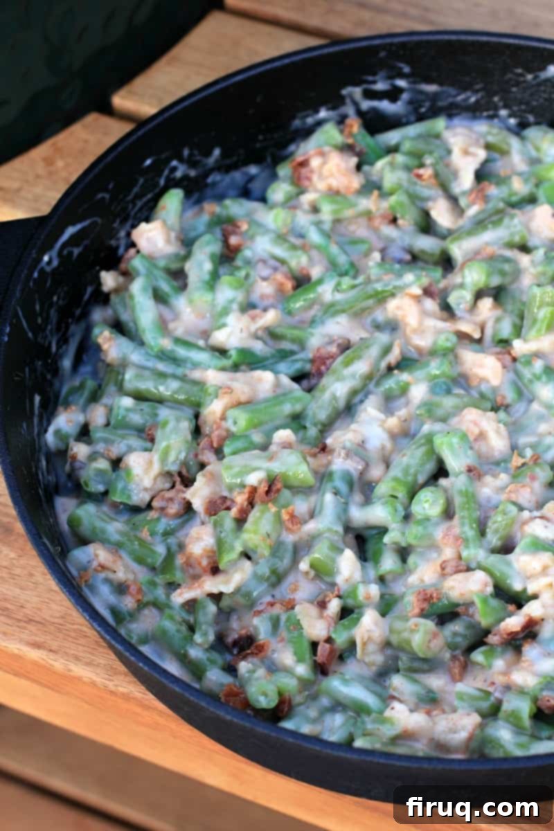 Grilled Green Bean Casserole with Crispy Bacon 6 Uncooked green bean casserole with bacon and onions in a cast iron skillet, prepared for grilling.