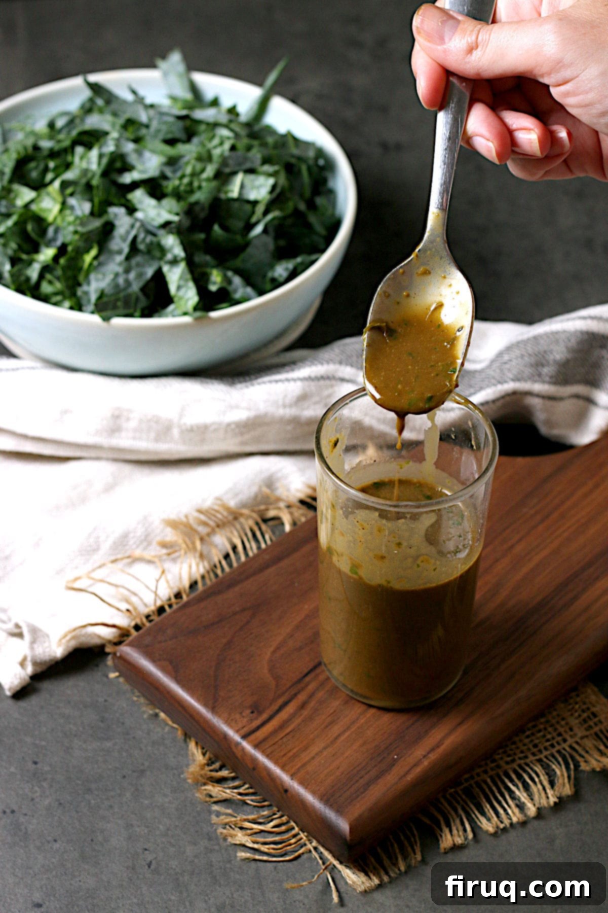 Spoonful of Basil Balsamic Vinaigrette A hand holding a spoonful of the perfectly blended Basil Balsamic Vinaigrette, showcasing its creamy, emulsified texture.