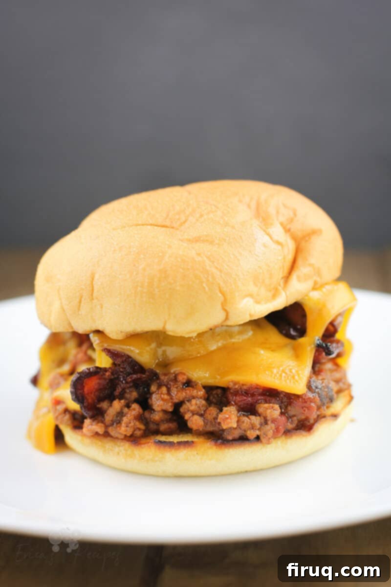 Grilled Beer-Infused Bacon Cheddar Joes 2 Assembled grilled sloppy joe in a toasted bun with melted cheddar and crispy bacon, served on a white plate