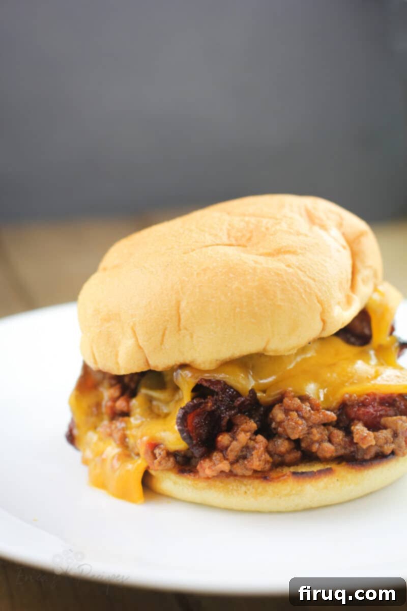 Grilled Beer-Infused Bacon Cheddar Joes 11 Side view of a finished Bacon Cheddar Beer Grilled Sloppy Joe sandwich on a white plate