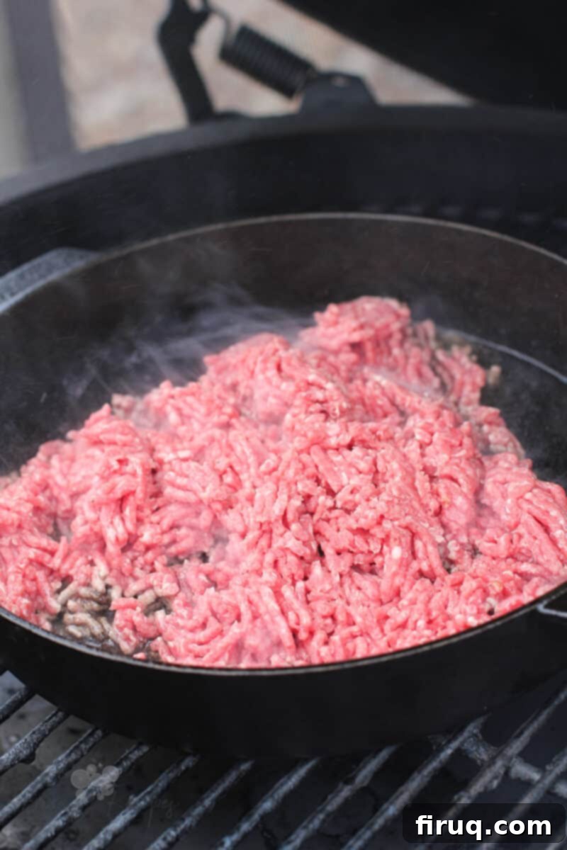 Grilled Beer-Infused Bacon Cheddar Joes 4 Ground beef browning in a cast iron skillet on the grill, ready for sauce ingredients