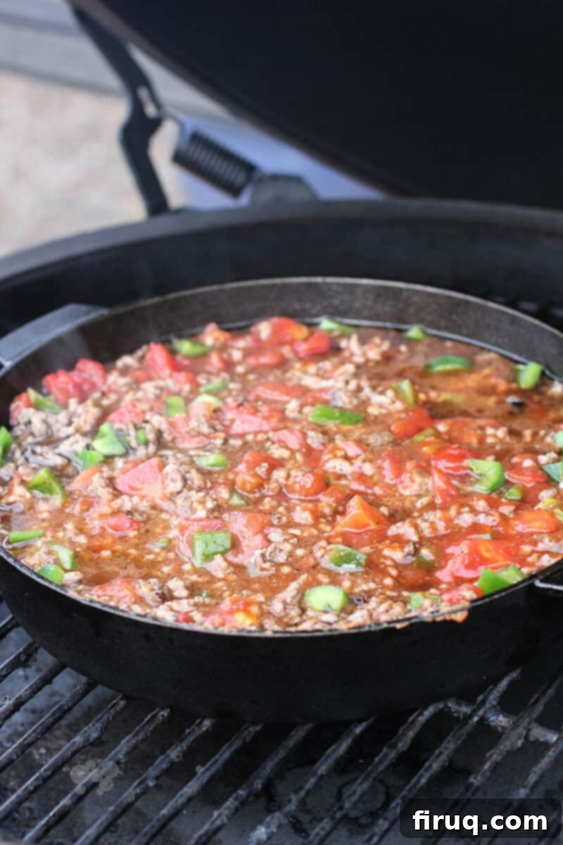 Grilled Beer-Infused Bacon Cheddar Joes 10 Assembled sloppy joe ingredients simmering in a cast iron pan on a Big Green Egg grill grate
