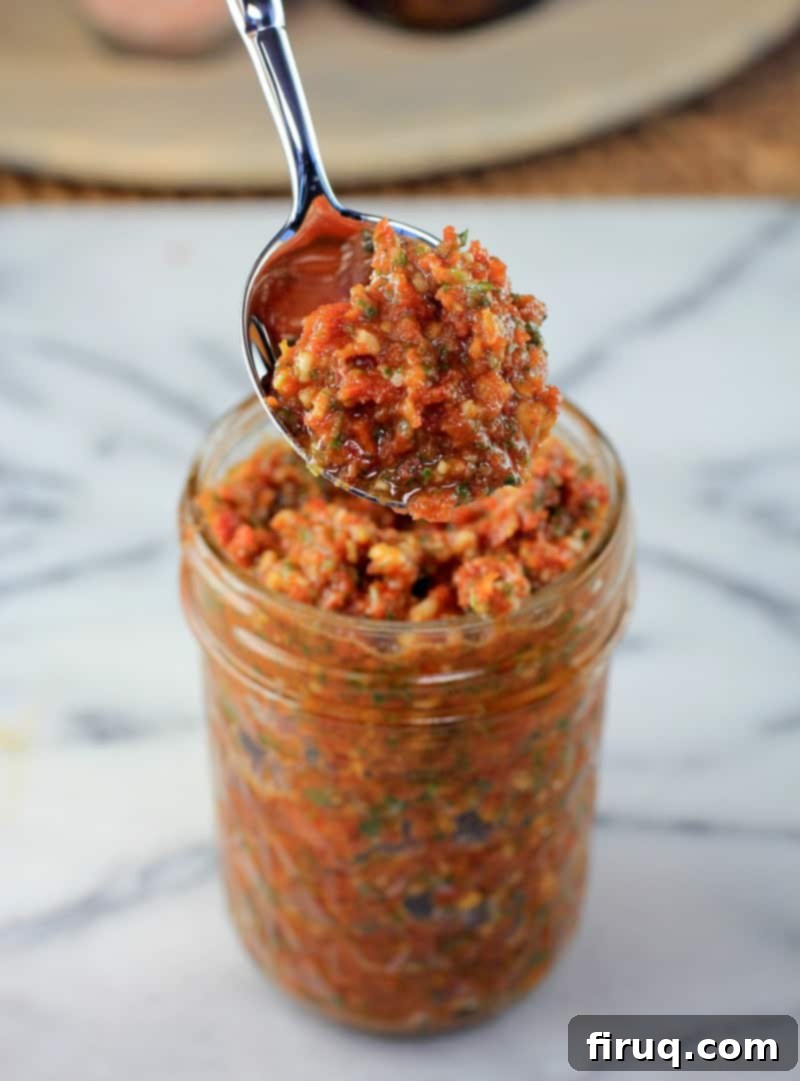 Rich Sun Dried Tomato Pesto Pasta 7 spoon lifting sun dried tomato pesto from a mason jar