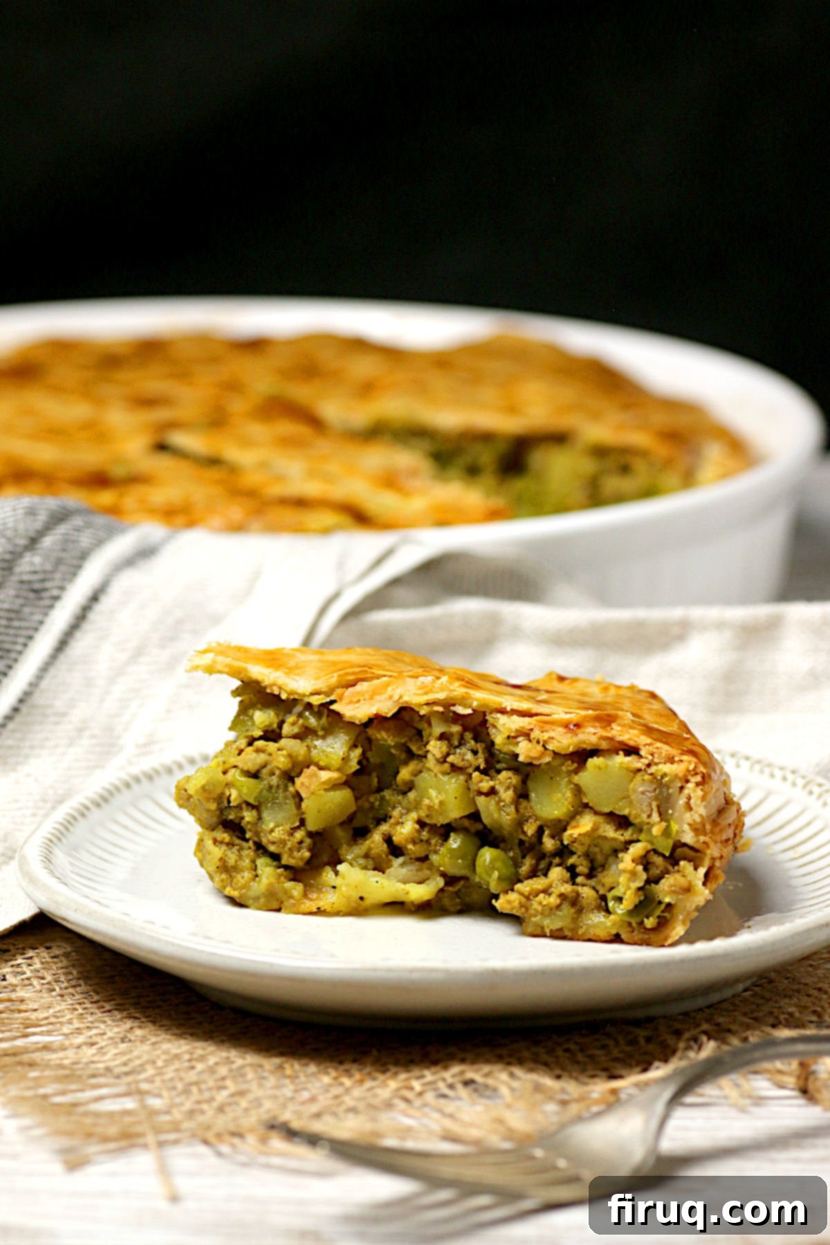 Slice of Chicken Samosa Pie A slice of Chicken Samosa Pie on a small white plate.