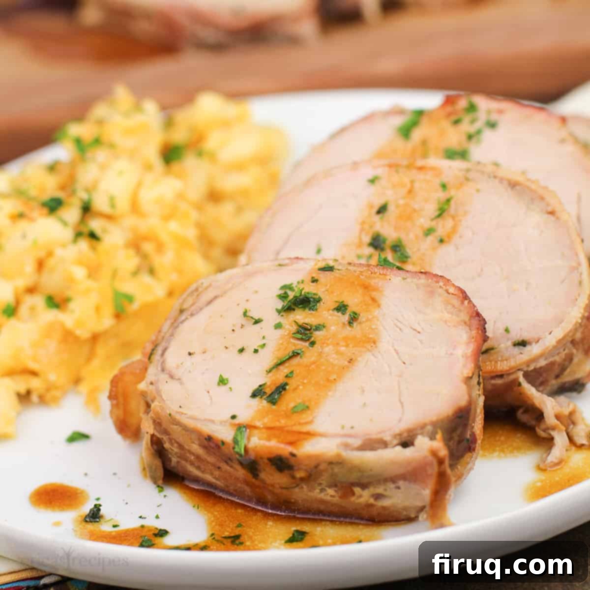 Easy Weeknight Roasted Pork Tenderloin 11 sliced roast pork tenderloin on white plate, sauce spooned over
