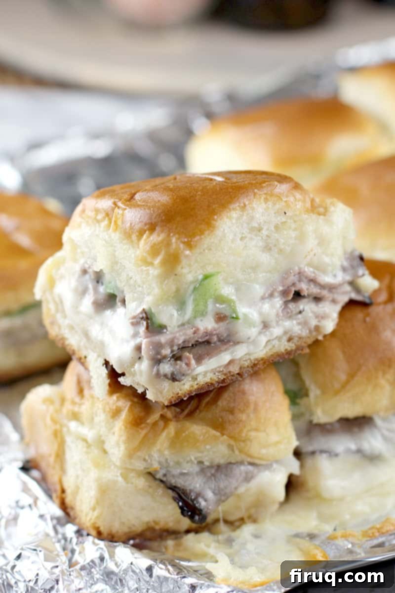 Grilled Philly Cheesesteak Bites 2 One grilled Philly cheesesteak slider stacked on another, showcasing the roast beef, bell pepper, and melted cheese filling within the toasted Hawaiian roll.