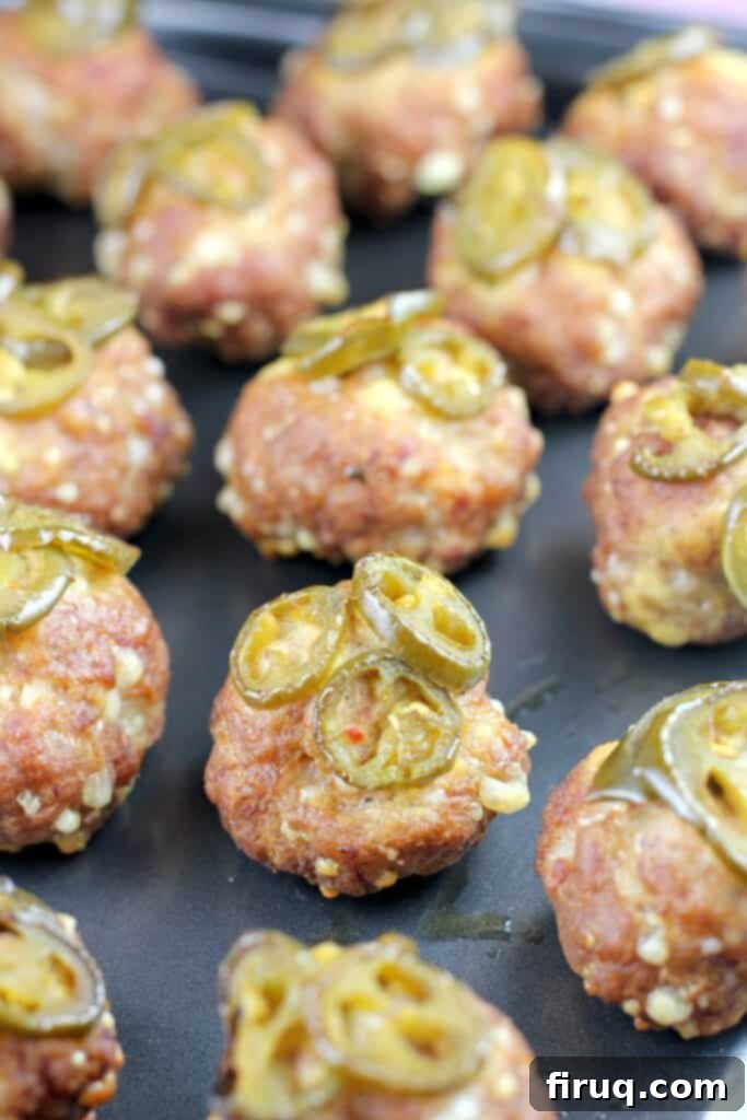 Aromatic Grilled Honey Thyme Biscuits 3 Smoked sausage balls with jalapeño garnish on a metal tray.
